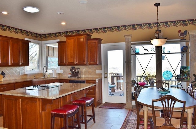 kitchen featuring backsplash, light stone countertops, black electric cooktop, and a sink