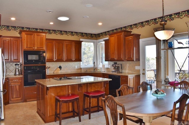 kitchen featuring backsplash, a center island, brown cabinets, black appliances, and a sink