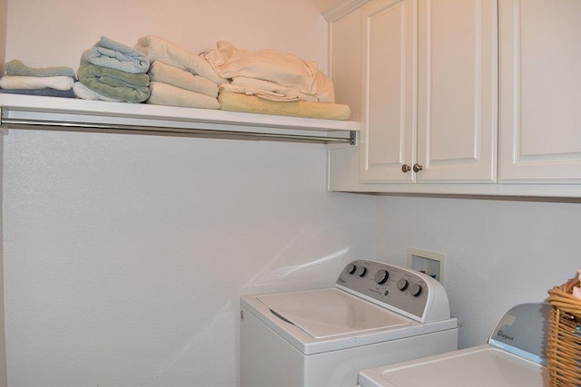 clothes washing area with washing machine and clothes dryer and cabinet space