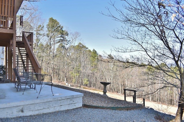 view of yard with a patio, a view of trees, and stairs