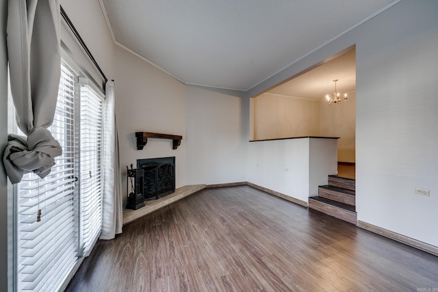 unfurnished living room with hardwood / wood-style floors, a notable chandelier, and ornamental molding