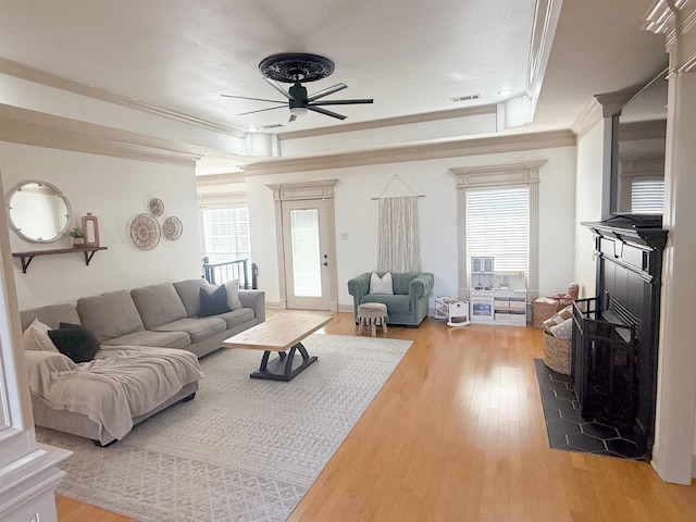 living room with ceiling fan, ornamental molding, a raised ceiling, and hardwood / wood-style floors