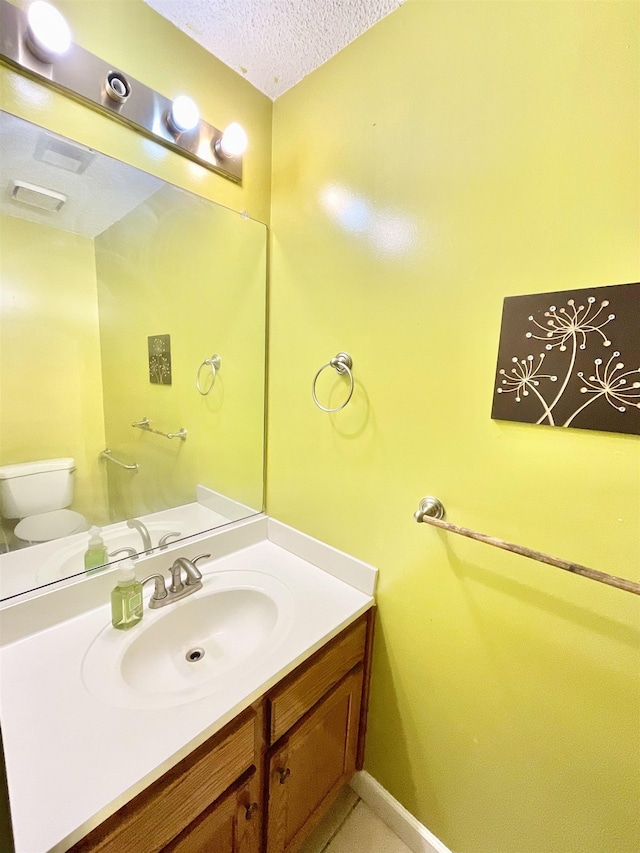 bathroom with vanity, a textured ceiling, and toilet