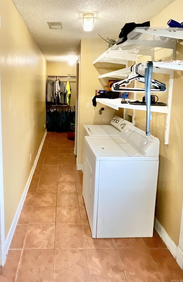 washroom featuring independent washer and dryer, tile patterned flooring, and a textured ceiling