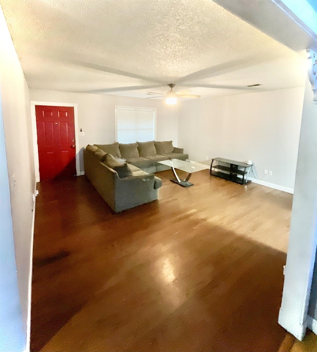 living room featuring hardwood / wood-style flooring, ceiling fan, and a textured ceiling
