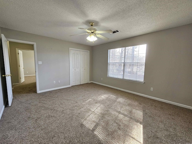 unfurnished bedroom featuring carpet flooring, a textured ceiling, ceiling fan, and a closet