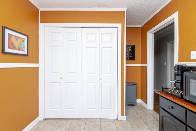 interior space with crown molding, a textured ceiling, and light tile patterned floors