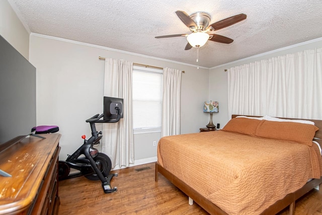 bedroom with a textured ceiling, ornamental molding, ceiling fan, and hardwood / wood-style flooring