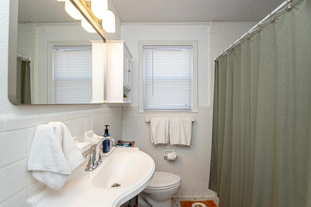 bathroom with crown molding, toilet, a textured ceiling, and tile walls