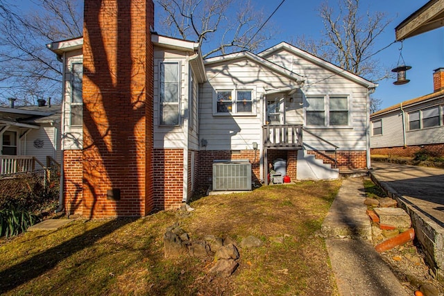 view of front of home with central AC unit and a front yard