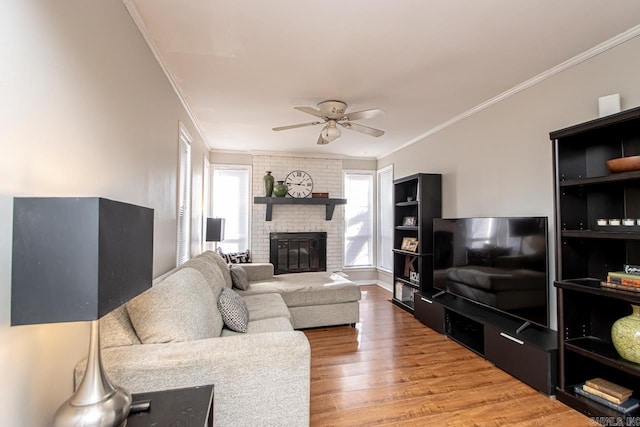 living room featuring hardwood / wood-style flooring, ornamental molding, a brick fireplace, and ceiling fan