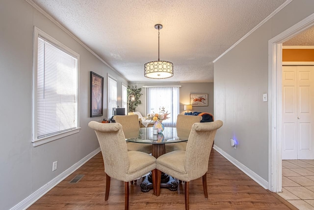 dining area featuring crown molding, wood-type flooring, and a textured ceiling