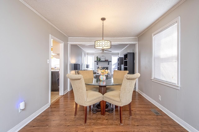 dining space with crown molding, hardwood / wood-style floors, and a textured ceiling