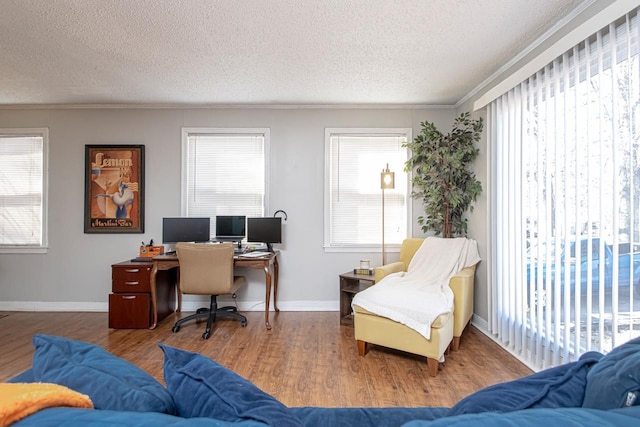 office featuring hardwood / wood-style floors, a wealth of natural light, ornamental molding, and a textured ceiling