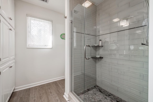 bathroom with hardwood / wood-style flooring and an enclosed shower