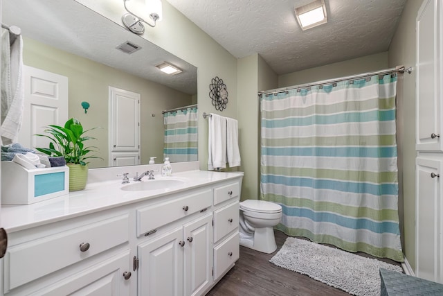 bathroom with vanity, hardwood / wood-style floors, toilet, and a textured ceiling