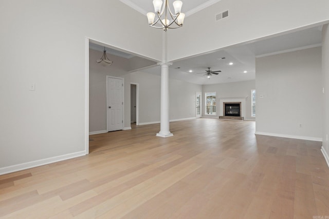 unfurnished living room with ceiling fan with notable chandelier, ornamental molding, decorative columns, and a high ceiling