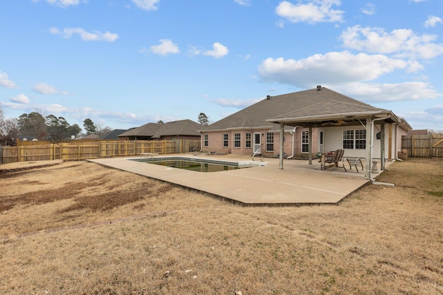 rear view of property featuring a fenced in pool, a yard, and a patio area