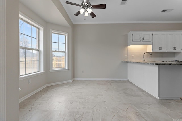 kitchen with white cabinetry, light stone countertops, ceiling fan, and crown molding