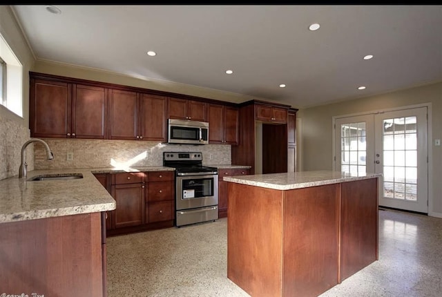 kitchen with sink, appliances with stainless steel finishes, tasteful backsplash, a kitchen island, and french doors