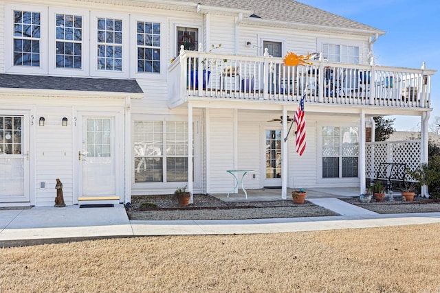 view of front facade featuring ceiling fan, a balcony, and a front lawn