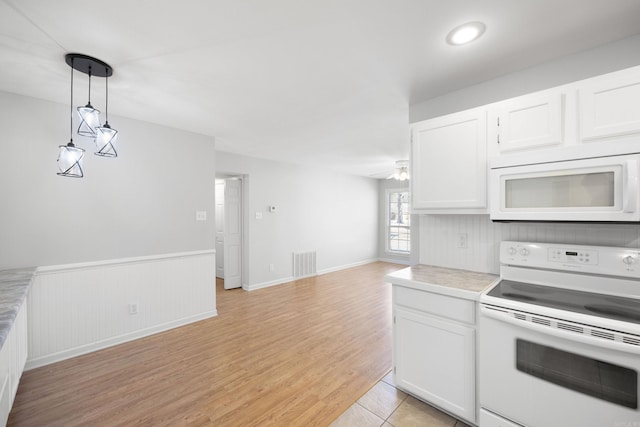 kitchen featuring white appliances, ceiling fan, hanging light fixtures, white cabinets, and light tile patterned flooring