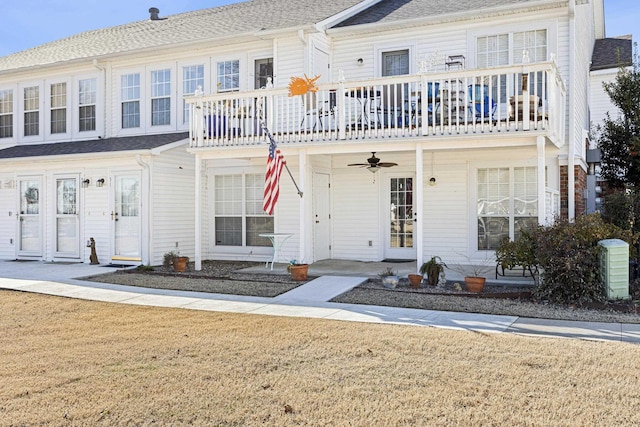 view of front of property featuring ceiling fan, a front yard, and a balcony