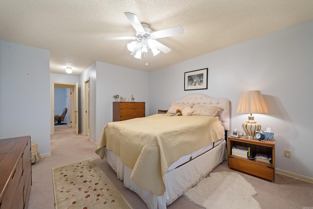 bedroom featuring ceiling fan, light colored carpet, and a textured ceiling