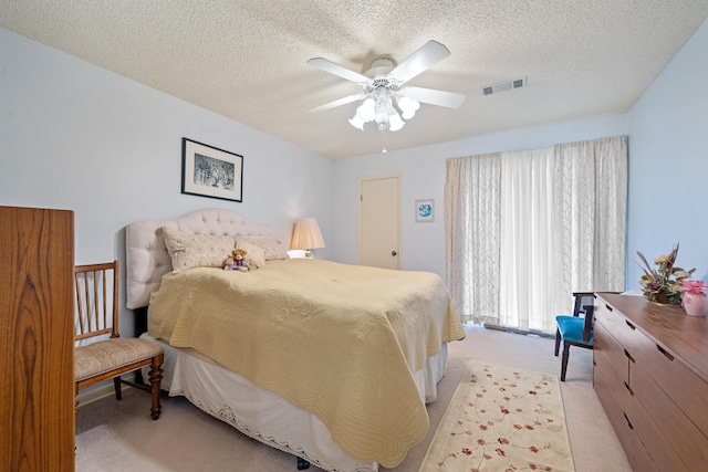 bedroom with ceiling fan, light carpet, and a textured ceiling