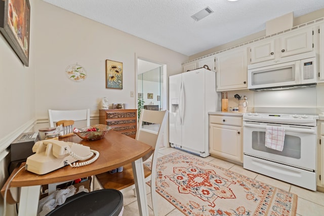 kitchen featuring light tile patterned floors, white cabinets, and white appliances