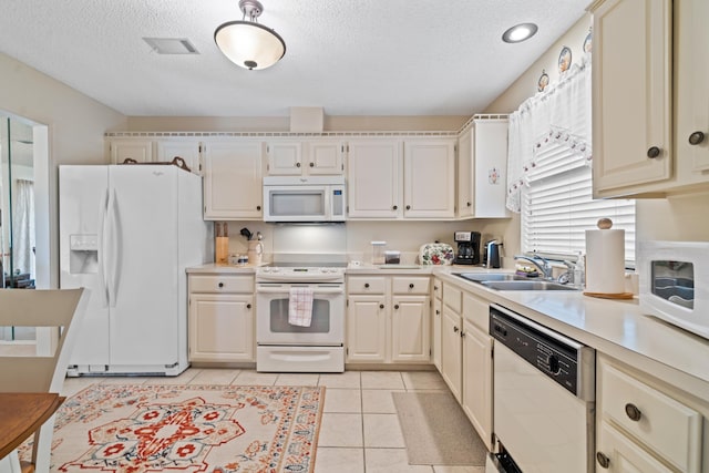 kitchen with white appliances, sink, a textured ceiling, and light tile patterned floors