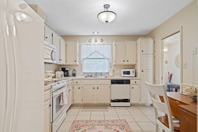 kitchen with white cabinetry, sink, light tile patterned floors, and white appliances