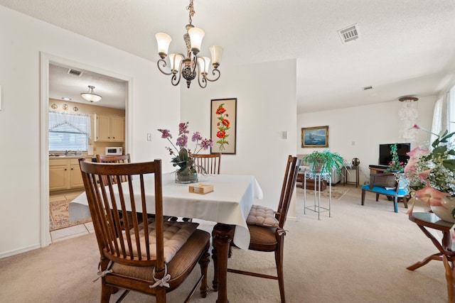 carpeted dining room featuring sink, a chandelier, and a textured ceiling