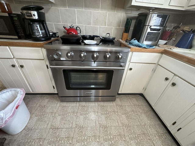 kitchen featuring white cabinetry, decorative backsplash, and high end stainless steel range