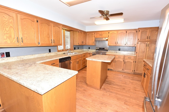 kitchen with a kitchen island, appliances with stainless steel finishes, sink, ceiling fan, and light hardwood / wood-style floors