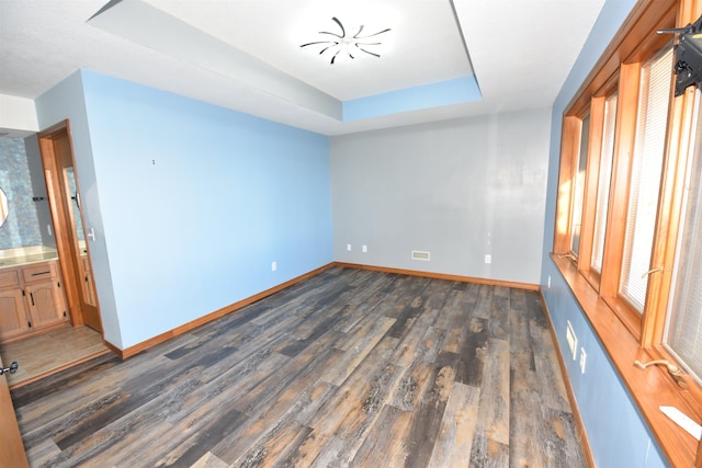 spare room featuring dark hardwood / wood-style flooring and a raised ceiling