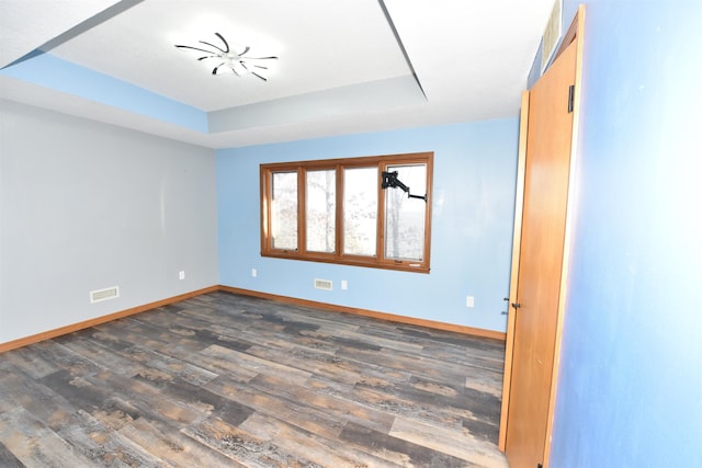 unfurnished room featuring dark wood-type flooring and a raised ceiling