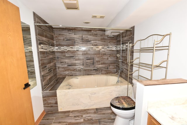 full bathroom featuring tiled shower / bath, vanity, and toilet