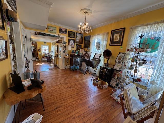 interior space featuring hardwood / wood-style flooring, crown molding, and an inviting chandelier