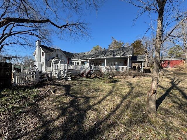 back of property with a yard and covered porch