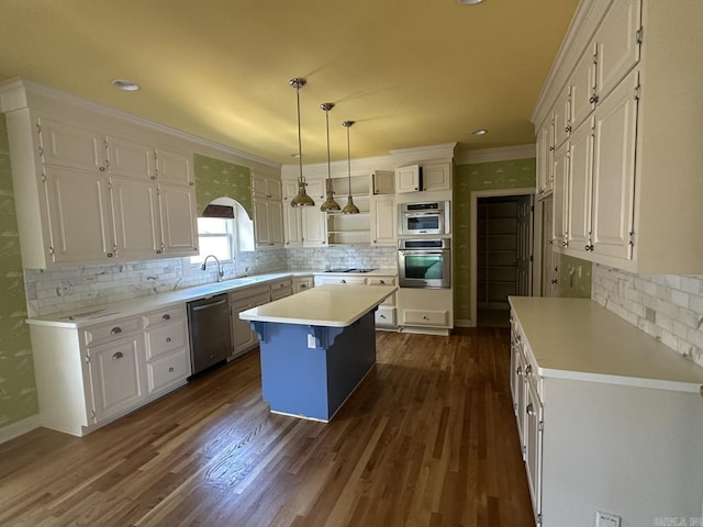 kitchen featuring white cabinetry, ornamental molding, appliances with stainless steel finishes, a kitchen island, and pendant lighting