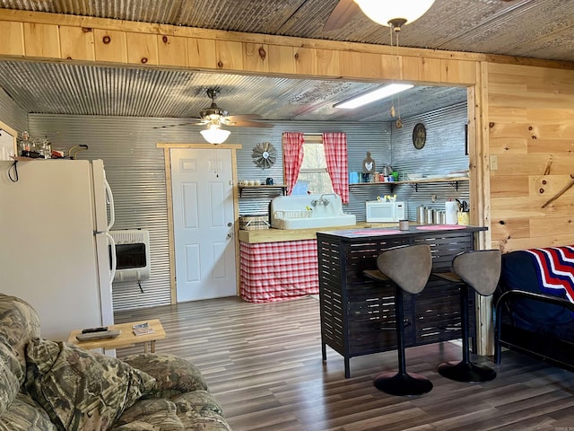 kitchen with heating unit, white appliances, wooden walls, and hardwood / wood-style flooring