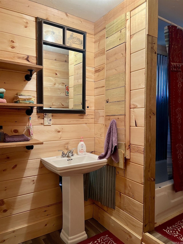 bathroom with a shower with shower curtain and wood walls