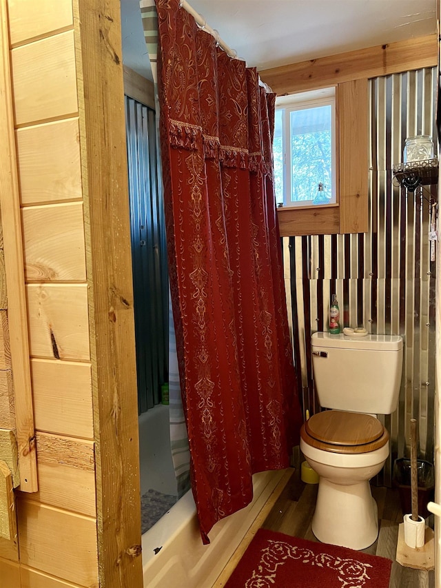 bathroom featuring shower / tub combo with curtain, hardwood / wood-style floors, and toilet