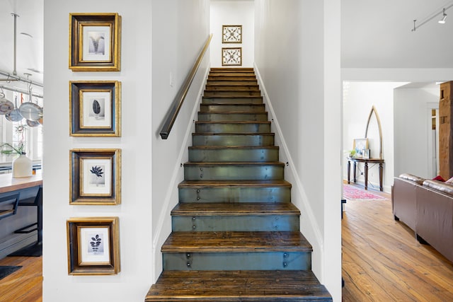 stairs with track lighting and wood-type flooring