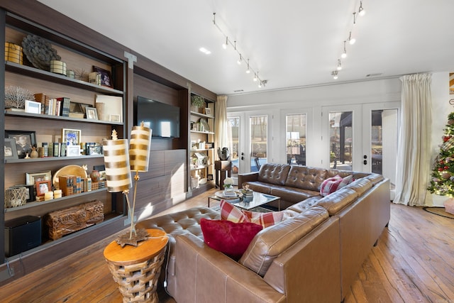 living room with built in shelves, light hardwood / wood-style flooring, and french doors