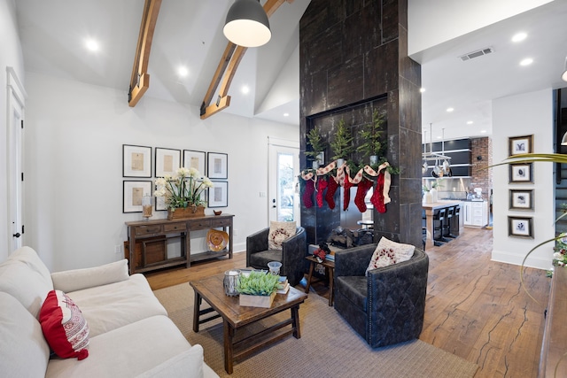 living room featuring hardwood / wood-style flooring, high vaulted ceiling, and beam ceiling