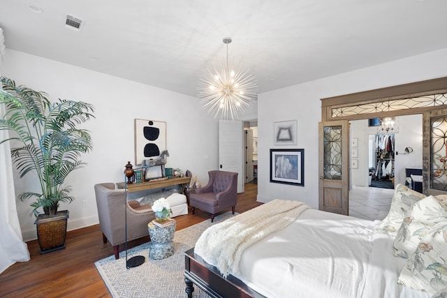 bedroom featuring an inviting chandelier, wood-type flooring, and a closet