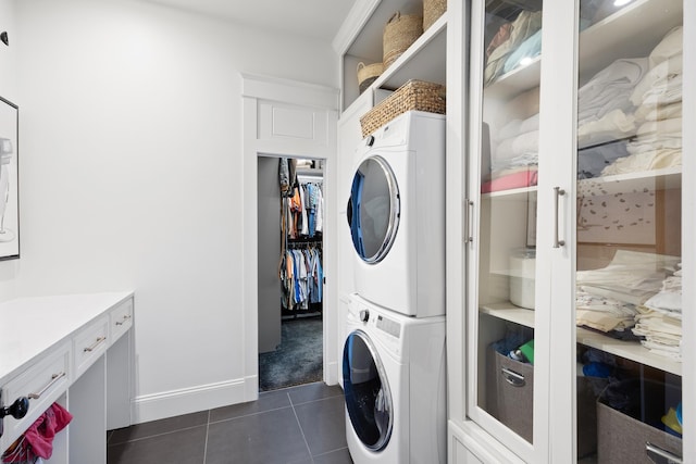 laundry area with stacked washer and dryer and dark tile patterned flooring