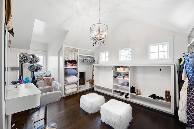 spacious closet with a notable chandelier, dark wood-type flooring, and vaulted ceiling